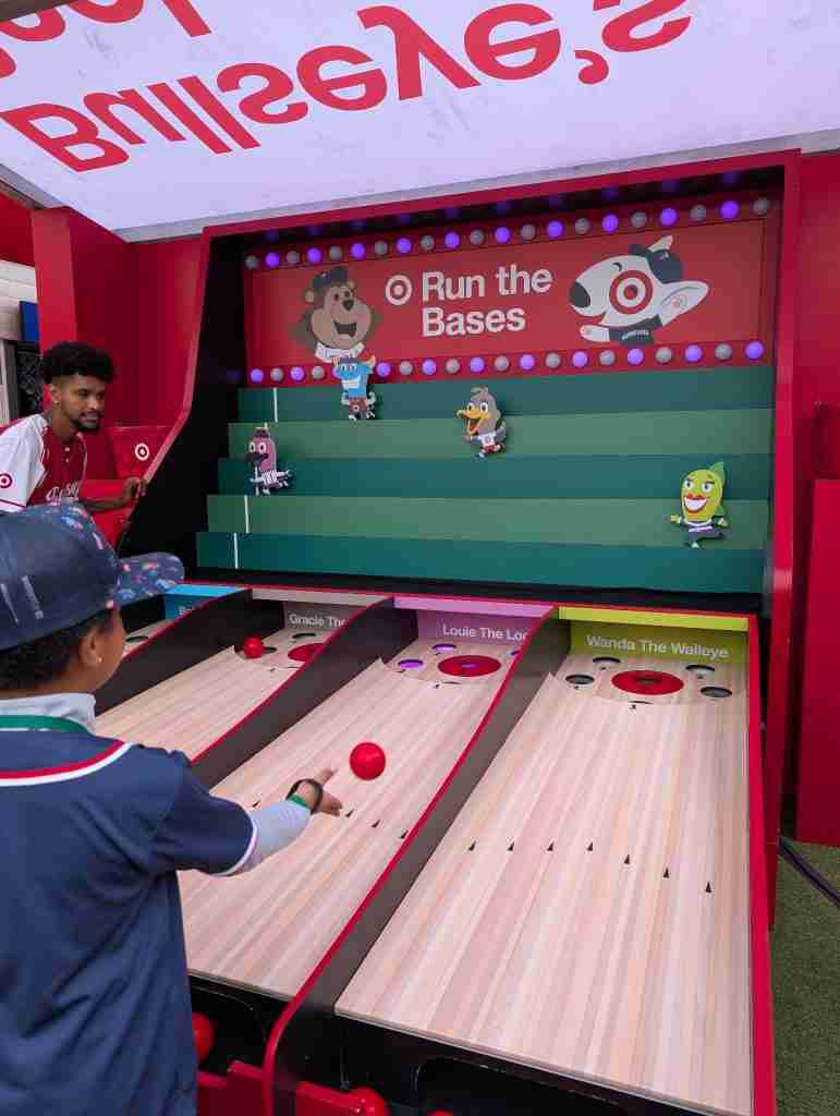 Boy rolls a red ball in a skee-ball character race at Target Field