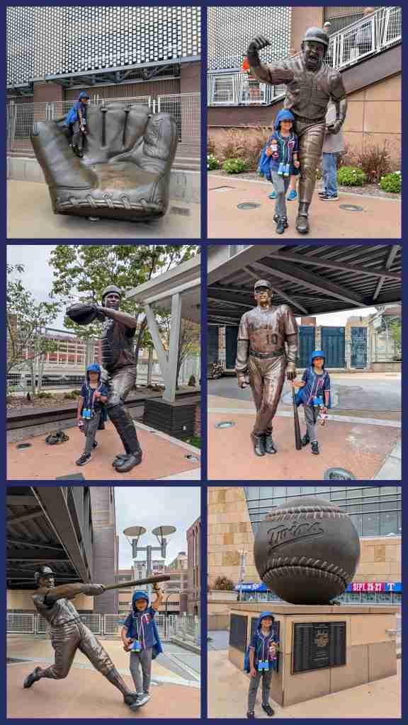 Boy poses with bronze Twins statues and a giant baseball glove outside Target Field
