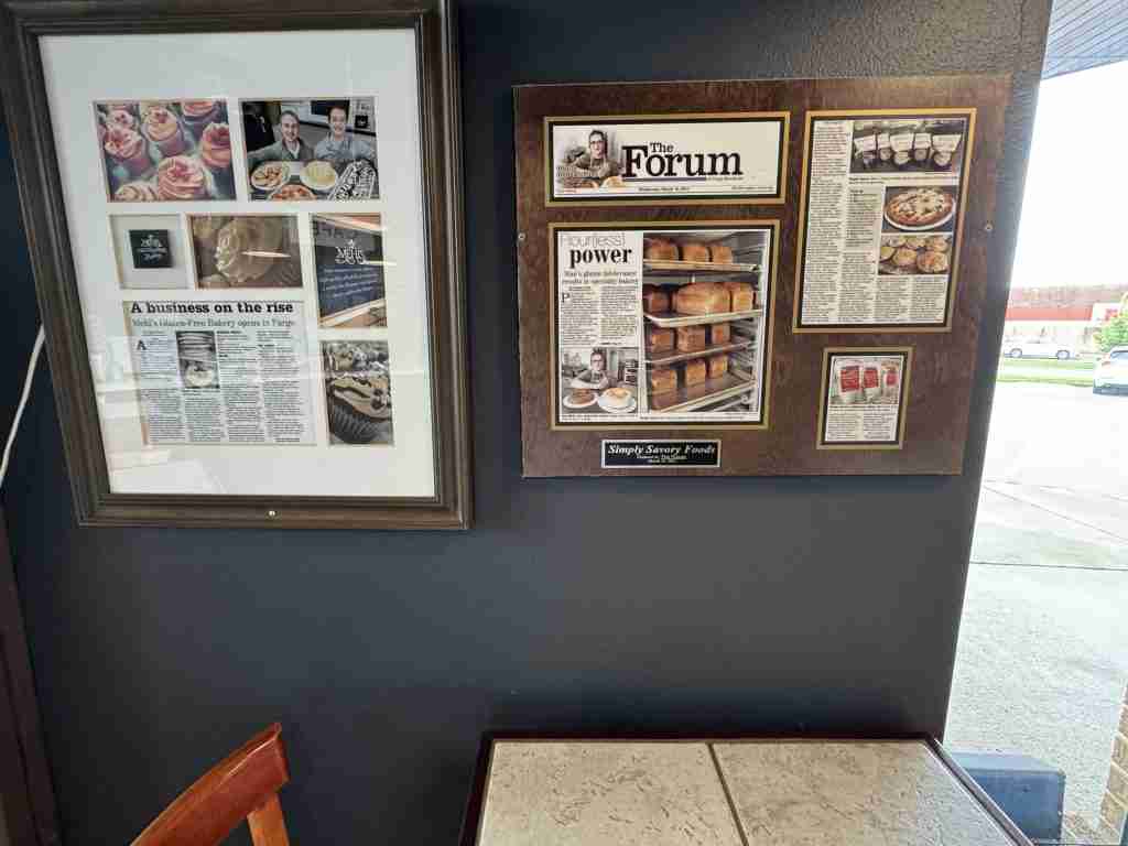 Framed newspaper clippings about Paul Mehl and Mehl's Gluten-Free Bakery hanging on the bakery wall
